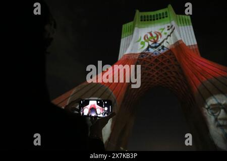 Teheran, Iran. 20 maggio 2024. Una donna iraniana scatta una foto di un video mapping del defunto progetto del presidente iraniano Ebrahim Raisi sulla torre Azadi (libertà) nella parte occidentale di Teheran. Il presidente iraniano Raisi, il ministro degli Esteri Amir-Abdollahian e altri sono morti in un incidente in elicottero il 19 maggio 2024, dopo una visita ufficiale vicino al confine con l'Azerbaigian. Il governo iraniano ha confermato le morti e ha annunciato cinque giorni di lutto pubblico. (Credit Image: © Rouzbeh Fouladi/ZUMA Press Wire) SOLO PER USO EDITORIALE! Non per USO commerciale! Foto Stock