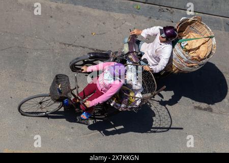 SAIGON, VIETNAM, dicembre 17 2017, Un uomo guida una moto carica di grandi cesti e spinge una donna in bicicletta con un grande cesto Foto Stock