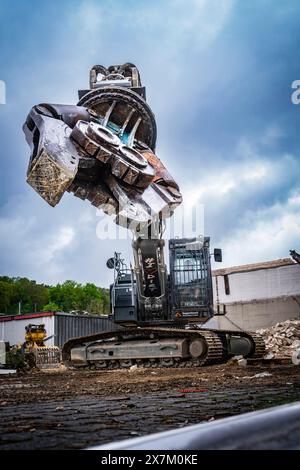 Grande escavatore con gigantesche pinze per demolizione in aria in un cantiere edile, circondato da materiali da demolizione e macerie, demolizione Foto Stock