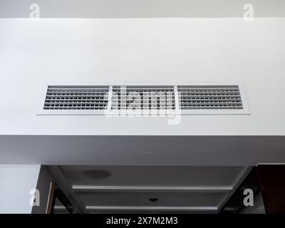 Vista frontale del sistema di ventilazione a parete dell'aria condizionata sul soffitto nella camera bianca e nera dell'hotel. Griglia per la ventilazione dell'aria della camera d'albergo sul W Foto Stock