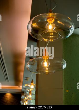 Splendida lampada di lusso retrò appesa al soffitto nel ristorante o nella caffetteria. Fotografia verticale di una ciotola di vetro lampada a sospensione dal design moderno e di lusso Foto Stock