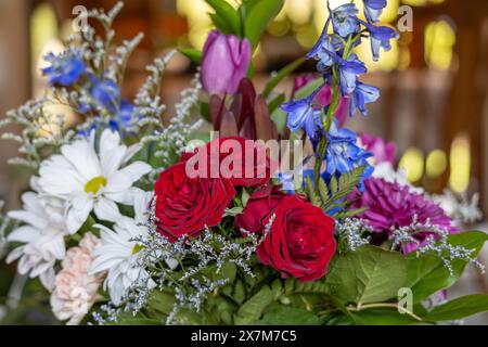 Primo piano sullo sfondo della disposizione del bouquet di un fioraio al coperto contenente fiori colorati, con sfondo sfocato Foto Stock