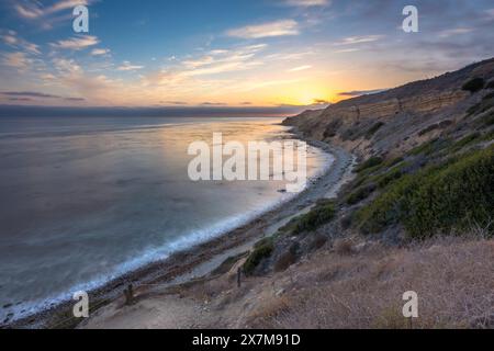 Imbarcati in un tranquillo viaggio lungo il Catalina Trail, dove il tranquillo tramonto illumina le aspre scogliere e lo splendore costiero di Ocean Trails Rese Foto Stock