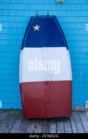 Bandiera acadiana dipinta sul fondo di una barca appoggiata contro un edificio a Shediac, New Brunswick, Canada Foto Stock