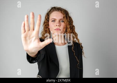 Donna con capelli ricci che tiene la mano in alto Foto Stock