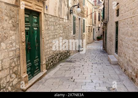 Belle strade vuote e strette e vecchi edifici tradizionali, case in pietra nella parte storica della città di Sibenico in Dalmazia, Croazia Foto Stock