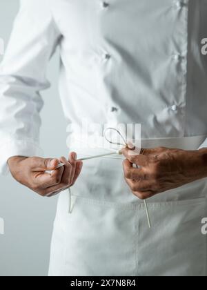 Chef che legano il grembiule a chef bianchi Foto Stock