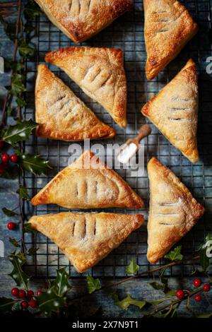 Boccali di frutta fatti con pasta sfoglia su una griglia circondata da holly. Foto Stock