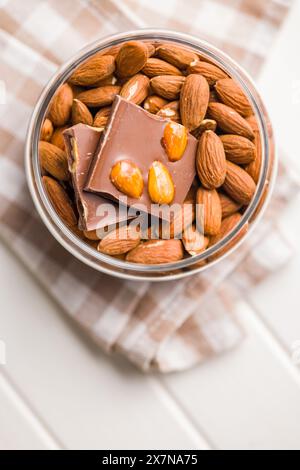 Barretta di cioccolato rotta con mandorle nel recipiente su un tavolo da cucina. Foto Stock