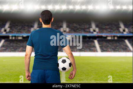 Immagine della vista posteriore ritagliata di un giovane giocatore che tiene una palla da calcio sotto le braccia a Parigi. Foto Stock