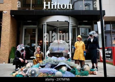 Londra, Regno Unito. 21 maggio 2024. Ocean Rebellion, un gruppo di attivisti ambientalisti, mette in scena una drammatica protesta contro John West Tuna al Blue Food Innovation Summit. Una lattina gigante etichettata come “JOHN WEST, TONNO CHUMPS” è strappata, rivelando “catture accessorie” di mercanti sanguinari, simboleggiando le vittime non intenzionali delle pratiche di pesca industriale. La protesta mette in evidenza l'uso controverso di dispositivi di aggregazione dei pesci alla deriva (dFADs) da parte delle attività di pesca provenienti dalla Thai Union, il proprietario di John West. Crediti: Joao Daniel Pereira/Alamy Live News Foto Stock