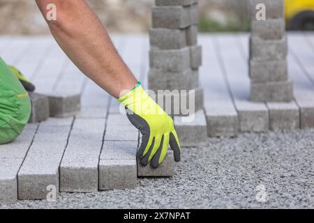 Processo di costruzione del marciapiede, posa del lavoratore su un percorso pedonale a interblocco, concetto industriale Foto Stock