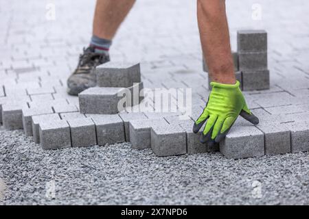 Processo di costruzione del marciapiede, posa del lavoratore su un percorso pedonale a interblocco, concetto industriale Foto Stock