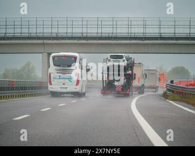 Piacenza, Italia - 22 aprile 2024 Una scena autostradale sotto un cielo coperto con auto e camion con segnaletica stradale e un cavalcavia, giornata di pioggia su Motorwa Foto Stock