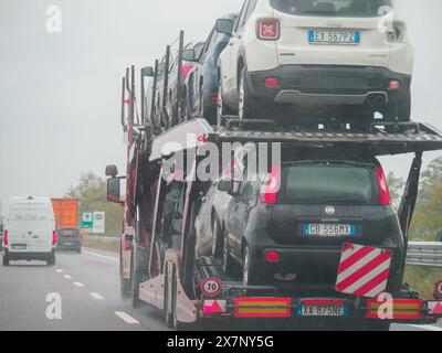 Piacenza, Italia - 22 aprile 2024 Una scena autostradale sotto un cielo coperto con auto e camion con segnaletica stradale e un cavalcavia, giornata di pioggia su Motorwa Foto Stock