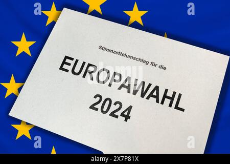 Germania - 21 maggio 2024: Busta cartacea per le elezioni europee del 2024 su una bandiera dell'Unione europea. FOTOMONTAGGIO *** Stimmzettelumschlag zur Europawahl 2024 auf einer Flagge der Europäischen Union. FOTOMONTAGE Foto Stock