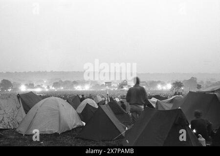 PALCO PIRAMIDALE, CAMPO PRINCIPALE, LOU REED, GLASTONBURY 92: La vista dal retro del Main Field mentre Lou Reed suona il Pyramid Stage al Glastonbury Festival, Pilton, Inghilterra, giugno 27 1992. La gente illuminava i bagliori e tutta la valle era piena di fumo, creando un'atmosfera spaventosa. A questo punto si poteva ancora accamparsi in fondo al campo principale. Non consentono più le tende sul retro del campo principale. Il festival è cresciuto così tanto che anche le colline vuote dietro il Pyramid Stage in questa foto sono ora parte del festival. Fotografia: ROB WATKINS Foto Stock