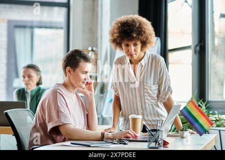 Diverse e graziose donne d'affari che lavorano insieme su un progetto in ufficio, bandiera dell'orgoglio. Foto Stock