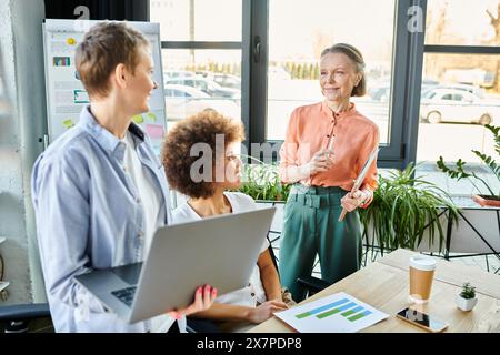 Diverse donne d'affari che collaborano intorno a un tavolo in legno in ufficio. Foto Stock