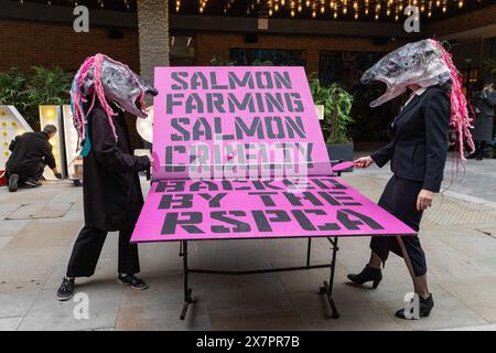 Londra, Regno Unito. 21 maggio 2024. Due attivisti ambientalisti della ribellione oceanica che indossano teste di salmone organizzano una partita di "pong rosa" fuori dal Blue Food Innovation Summit all'Hilton Hotel Bankside in segno di protesta contro l'allevamento di salmoni. Il gioco del "pong rosa" aveva lo scopo di evidenziare sia la crudeltà dell'industria agricola scozzese del salmone, compreso l'aumento dei tassi di mortalità, sia il coinvolgimento dell'Acquacoltura Stewardship Council (ASC), dei supermercati e degli oratori al Blue Food Innovation Summit. Crediti: Mark Kerrison/Alamy Live News Foto Stock