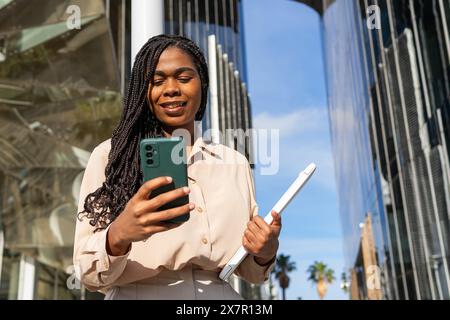 Una giovane donna ama trascorrere l'estate a Barcellona con gli amici, scrivendo al telefono con un sorriso e tenendo i documenti in mano Foto Stock
