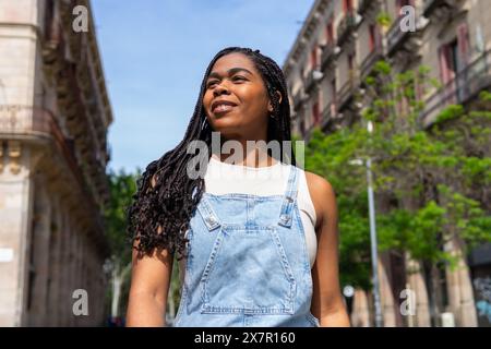 Una giovane donna sorridente gode di una giornata di sole a Barcellona con un abbigliamento casual in denim, incarnando il vibrante spirito dell'amicizia estiva Foto Stock