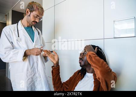 Un giovane medico maschile controlla i livelli di zucchero nel sangue di un paziente che sperimenta sintomi di ipoglicemia in una clinica moderna Foto Stock