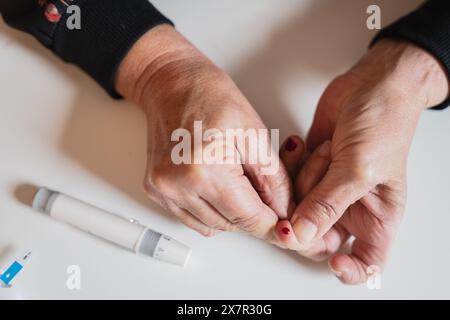 Primo piano di mani anziane in qualità di persona aiuta un anziano test dello zucchero nel sangue con un glucometro, sottolineando la cura per i diabetici anziani e la gestione dell'ipoglicico Foto Stock