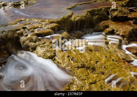 Foto ravvicinate mozzafiato che mostrano i colori e le texture unici e vivaci del terreno roccioso e dell'acqua corrente del fiume Riotinto, catturando Foto Stock