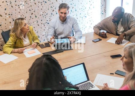 Team diversificato che collaborano a un progetto in un moderno spazio di coworking Foto Stock