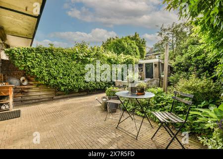 Un'incantevole area patio esterna adornata da spesse vigne verdi, con tavolo e sedie rustici, ideale per godersi un tranquillo pomeriggio in una casa Foto Stock