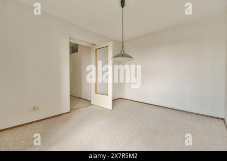 Spaziosa camera vuota con pareti bianche e lampada a sospensione minimalista, ideale per ambienti di design interno Foto Stock