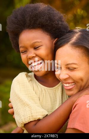 Amate madre e figlia ridendo e abbracciando all'aperto in campagna o in giardino Foto Stock