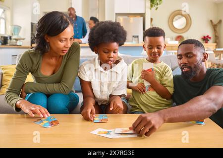 Famiglia in casa con carte da gioco con nonni in background Foto Stock