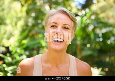Testa e spalle Ritratto di donna matura sorridente e sicura di sé con capelli corti in piedi all'aperto Foto Stock