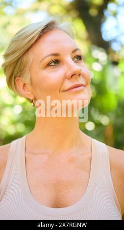 Testa e spalle Ritratto di donna matura sorridente e sicura di sé con capelli corti in piedi all'aperto Foto Stock