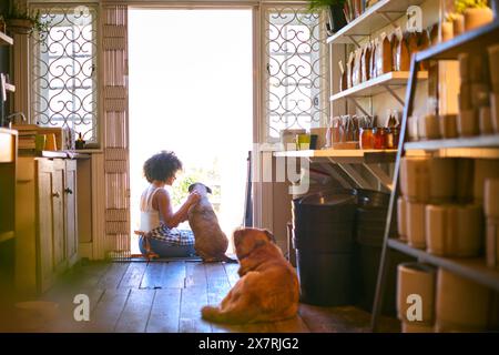 Donna con cani da compagnia seduti davanti all'ingresso di un supermercato senza plastica sostenibile Foto Stock