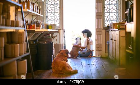 Donna con cani da compagnia seduti davanti all'ingresso di un supermercato senza plastica sostenibile Foto Stock