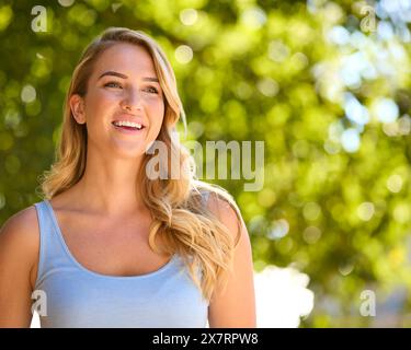 Testa e spalle Ritratto di donna sorridente all'aperto che si rilassa in campagna guardando la fotocamera Foto Stock