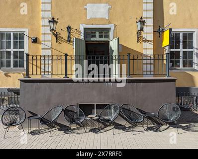 Sedie in vimini e tavolini in una caffetteria all'aperto nella città vecchia di riga, in Lettonia. Foto Stock