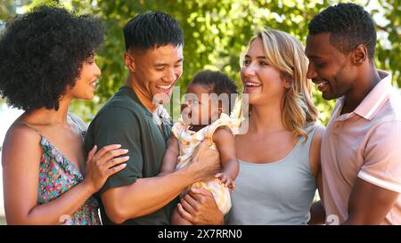 Ritratto della famiglia multi-razziale e degli amici che abbracciano il bambino all'aperto in campagna in gruppo insieme Foto Stock