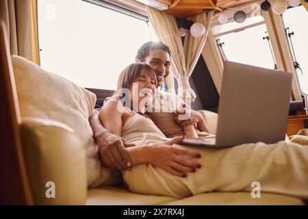 Un uomo e una donna seduti a stretto contatto su un divano, entrambi concentrati sullo schermo di un notebook davanti a loro. Foto Stock