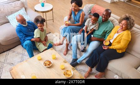 Famiglia multi-generazione seduto nella sala di casa a guardare la TV insieme Foto Stock