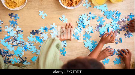 Primo piano di bambini al chiuso a casa che fanno il puzzle di Jigsaw insieme Foto Stock