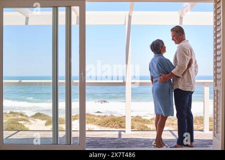 Una coppia matura amorevole che abbraccia la Beachfront House con vista sull'oceano per le vacanze estive Foto Stock