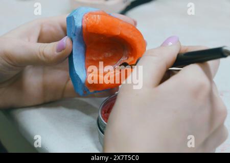 L'odontotecnico crea una base di cera e aggiunge cera per formare lo stampo. Concetto odontoiatrico Foto Stock