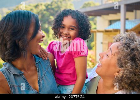 Ritratto della famiglia femminile di tre generazioni che ride e sorride in piedi all'aperto in campagna Foto Stock