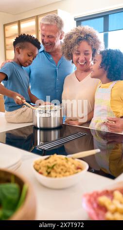 I nipoti aiutano i nonni a preparare i pasti in Kitchen at Home e divertiti insieme Foto Stock