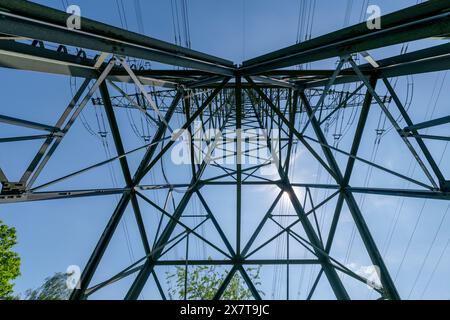 Un accattivante primo piano che cattura i motivi geometrici e la bellezza industriale di un pilone elettrico sullo sfondo del cielo. ⚡ #PowerGridIco Foto Stock