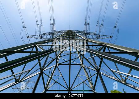 Una vista accattivante di un pilone ad alta tensione contro il cielo azzurro incontaminato, un promemoria del ruolo essenziale dell'elettricità nella nostra vita quotidiana #BL Foto Stock